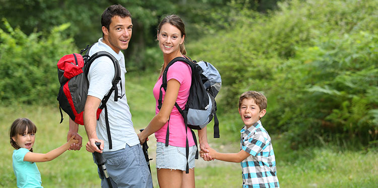 Family picture, husband, wife, young boy and girl smiling while walking in the park